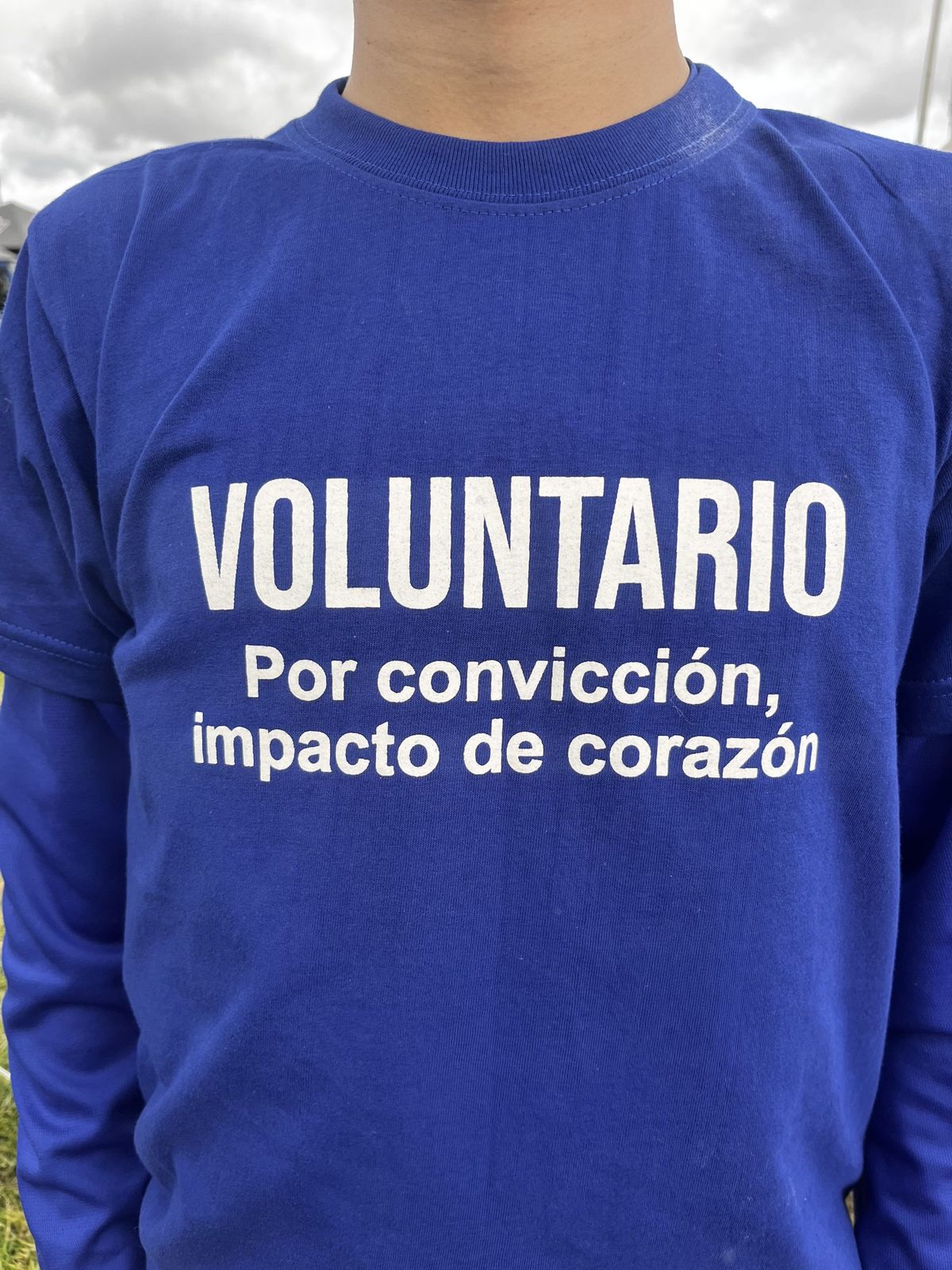 Una persona con la camiseta azul de voluntario de la fundación, que dice «Voluntario. Por convicción, impacto de corazón».